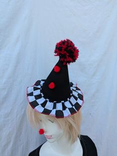 a mannequin head wearing a black and white hat with red pom - poms