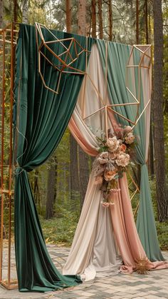 an outdoor wedding ceremony with green drapes and flowers on the altar, surrounded by tall trees