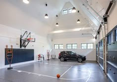 an indoor basketball court with a car parked in the center and several basketball hoops hanging from the ceiling