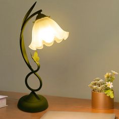 a desk lamp sitting on top of a wooden table next to a potted plant