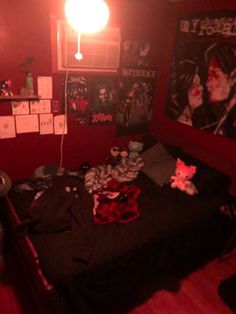 a bedroom with red walls and posters on the wall, a bed covered in black sheets