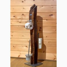 a wooden pole with two rolls of toilet paper hanging on it's side and a cup holder in the middle