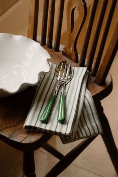 two green and white striped napkins sitting on top of a wooden chair next to a plate