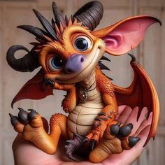 a hand holding a small toy dragon in it's right hand with big eyes