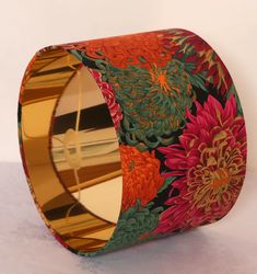 a close up of a metal object with flowers on it's side and gold rim