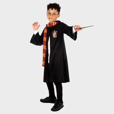 a young boy dressed as harry potter holding a wand and pointing to the side with both hands