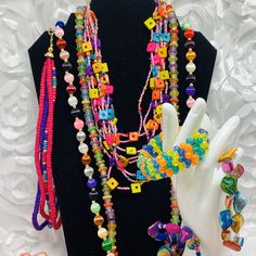 a hand is holding a multi - colored beaded necklace and bracelet set on a mannequin