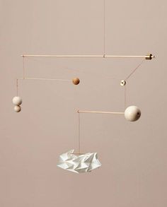 an origami mobile with balls hanging from it's sides and two strings