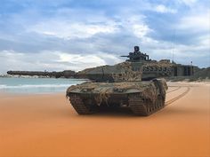 an army tank is driving on the beach