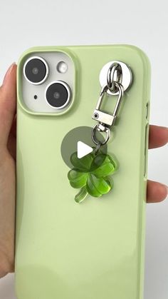 a person holding an iphone case with a keychain attached to the back of it