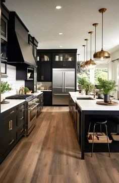 a kitchen with black cabinets and white counter tops, wood flooring and pendant lights