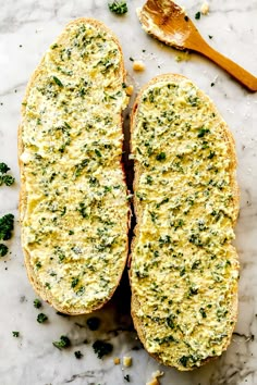 two pieces of bread with cheese and broccoli on it next to a wooden spoon