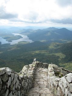 a stone stairway leading to the top of a mountain with a lake in the distance