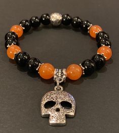 This fun to wear Halloween Theme charm bracelet features 8mm black onyx and orange quartz beads with antique silver spacers and barrel bead. The beautiful 25mm antique silver sugar skull charm really makes this a great bracelet to celebrate Halloween, Dia de los Muertos or anytime that makes you happy. An additional selection of charms is available in the pull down menu. The bracelet is strung on 1mm Ninja stretch cord and easily rolls over your hand to rest on the wrist. The 6.5 inch bracelet is featured in the photograph of my hand but I can custom make any size you need. Just select the size you need or convo me with your special request. Please know that each bracelet I make is truly one-of-a-kind and made with a Touch of Magick. To determine what size you need, use a tape measure, or Halloween Beaded Bracelet, Halloween Bracelet Ideas, Skull Bead Jewelry, Halloween Jewelry Diy, Halloween Beaded Jewelry, Heishi Jewelry, Halloween Sugar Skull, Orange Quartz, Clay Bracelets