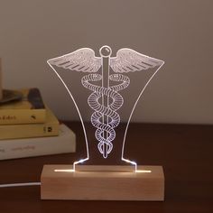 an illuminated cadus symbol on a wooden stand next to some books and a lamp