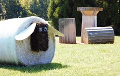 a sheep is standing in the grass near some sculptures