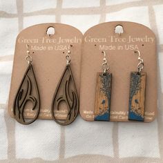 three pairs of earrings with wood and metal details on the earwires are displayed in front of a card