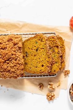 a loaf of cake sitting on top of a cooling rack next to a bowl of nuts