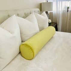 a bed with white pillows and a yellow pillow