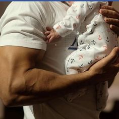 a man holding a baby in his arms and wearing a white shirt with anchors on it