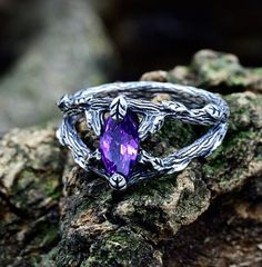 a purple stone ring sitting on top of a rock