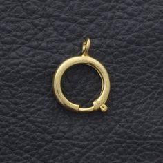 a small gold ring on a black leather textured surface with the word'o'written in cursive writing