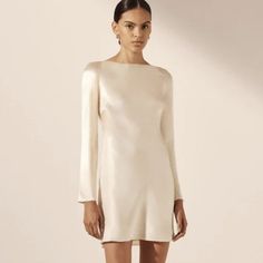 Shona Jo Long Sleeve Backless Mini Dress In Cream In A Lenzing Ecovero With Luxurious Satin Finish. Nwt From Bridal Collection Silk Touch Fabric Luxurious Sheen Round Neckline With Tie Closure Long Slim Sleeves Low Open Back With Cowl Detail Mini Length, Cut On The Bias Medium Weight, Non-Stretchy Woven 58% Lenzing Ecovero 42% Viscose Lined Designed In Australia Available Online At Full Price Shona Joy Short Dress, Silk Slip Wedding Dress With Sleeves, Champagne Mini Dress With Sleeves, Cream Long Sleeve Silk Dress, A Line Cream Dress, Minimal White Dress With Sleeves, Long Sleeve Rehearsal Dress, Winter Engagement Party Dress, Winter Wedding Rehearsal Outfit