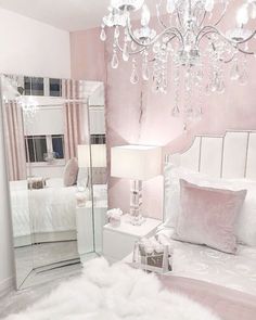 a bedroom decorated in pink and white with a chandelier hanging from the ceiling