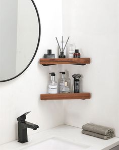 a bathroom sink with two wooden shelves on the wall above it and a round mirror