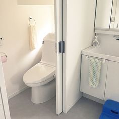 a white toilet sitting next to a sink in a bathroom under a mirror and towel rack