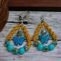 two pairs of earrings with blue and yellow beads on top of wooden table next to basket