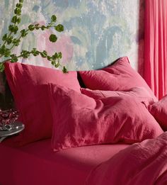 a bed covered in pink sheets and pillows