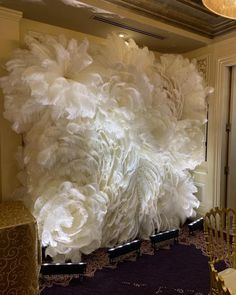 large white paper flowers are on display in a room with chairs and tablecloths