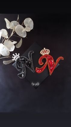 two brooches are sitting on top of a black card with red and white designs