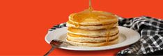 a stack of pancakes on a plate with syrup being drizzled over them