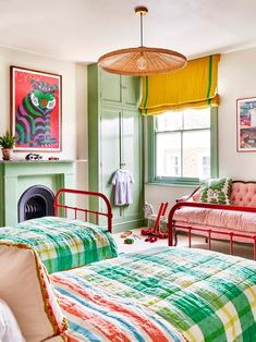 two beds in a room with green walls and pictures on the wall above them, next to a fire place