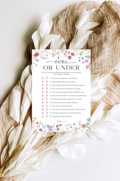 a wedding order card sitting on top of a white table cloth with feathers around it