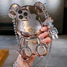 a person holding up a silver cell phone case with chains attached to it's sides