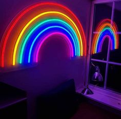 a room with neon lights in it and a rainbow wall hanging on the wall next to a window