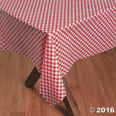 a red and white checkered table cloth on top of a wooden chair in front of a wood floor