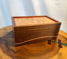 a wooden box sitting on top of a piece of wood next to a green object