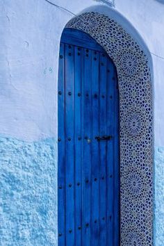 an open blue door on the side of a white and blue building with intricate designs