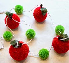 several pom - poms are arranged in the shape of an apple on a string