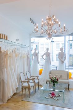 a room filled with lots of white dresses and mannequins in front of a window