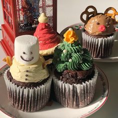 three decorated cupcakes sitting on top of a plate next to a phone booth