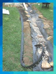 a garden hose laying on top of some rocks and gravel next to a fenced in area