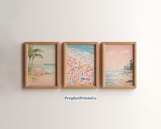 three framed pictures hang on the wall in front of a white wall with an ocean scene