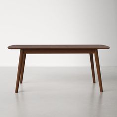 a wooden table sitting on top of a cement floor next to a white wall in an empty room