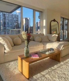 a living room filled with furniture and large windows overlooking the cityscape in the background