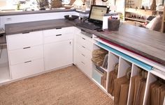 a laptop computer sitting on top of a wooden table in a kitchen next to white cabinets